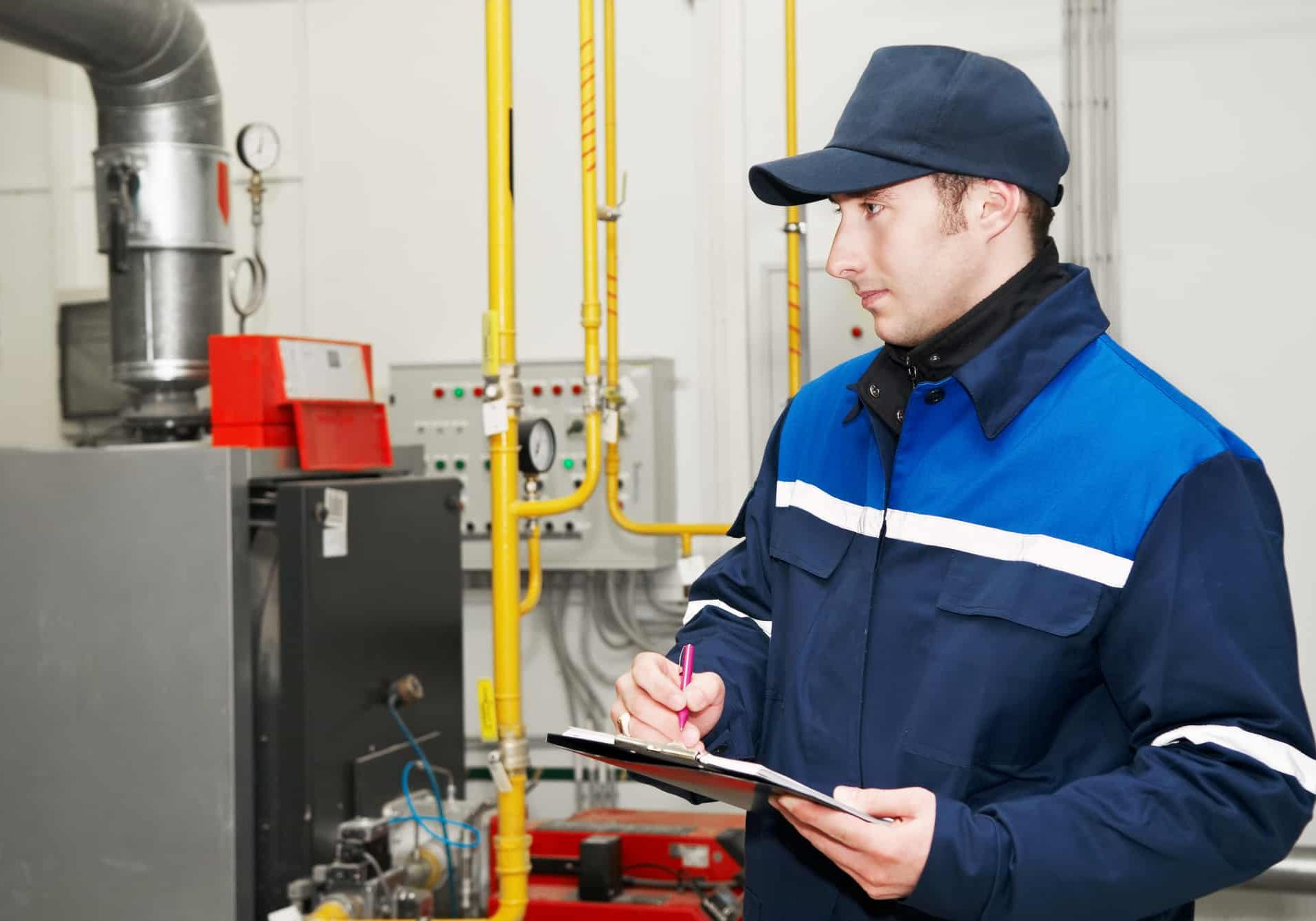 Maintenance engineer checking technical data of heating system equipment in a boiler room